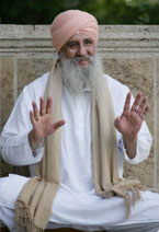Guru Dev sitzend,lachend und Handflächen zum Betrachter